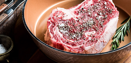 Raw steak cooking inside Gotham Steel™ Hammered Pan